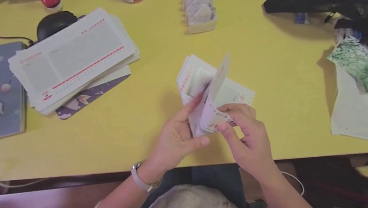 Predicted first-person view of two hands manipulating paper from a world model trained on 30,000 hours of egocentric video